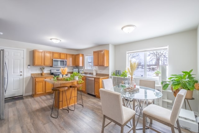 kitchen with a kitchen island, a breakfast bar, light wood-style flooring, stainless steel appliances, and a sink