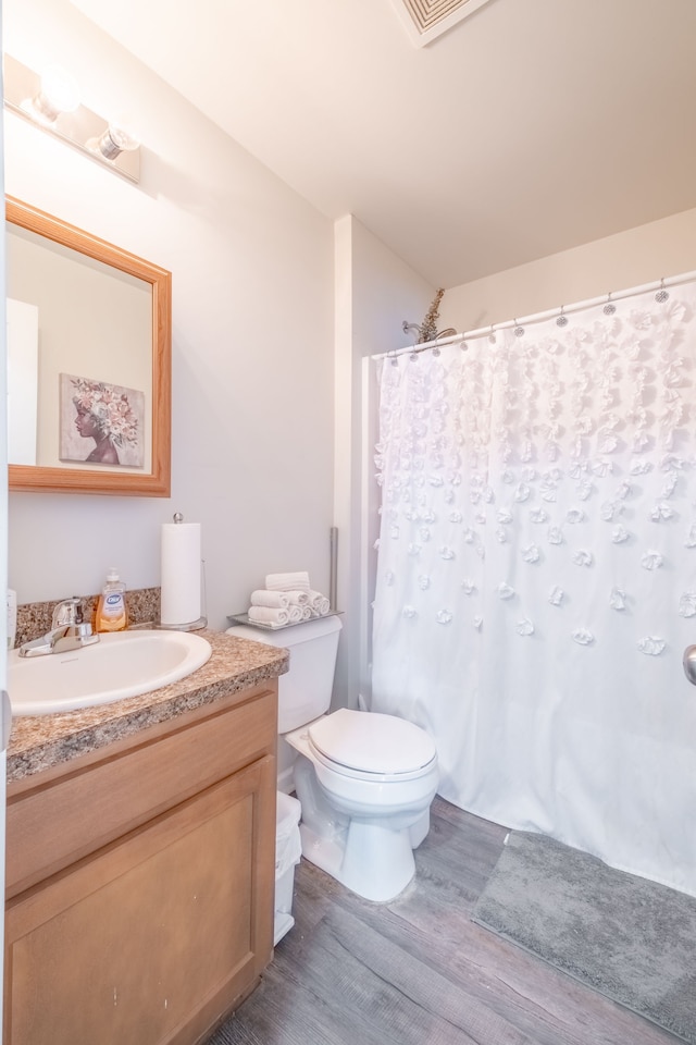 bathroom with toilet, vanity, a shower with shower curtain, and wood finished floors