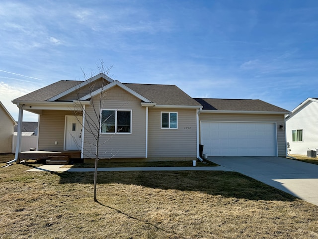 view of front facade with a front yard, a garage, driveway, and roof with shingles