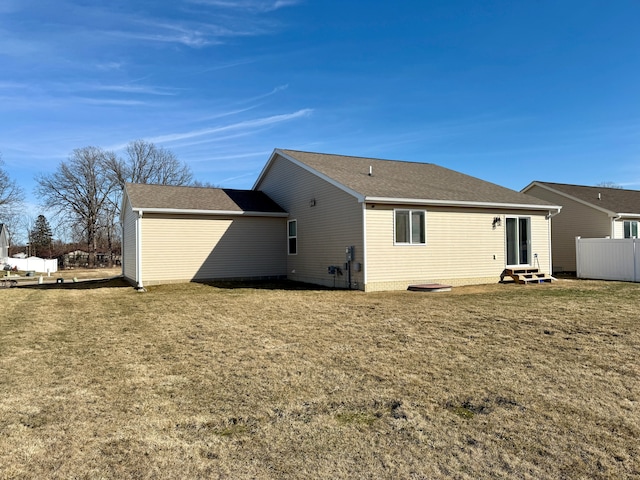 back of property with fence, a lawn, roof with shingles, and entry steps