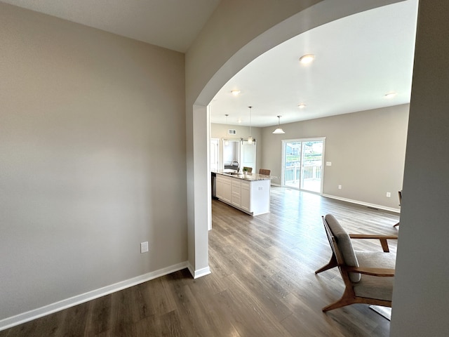 interior space with hardwood / wood-style floors, pendant lighting, white cabinetry, and light stone counters