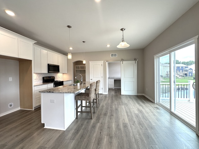 kitchen with black range with gas stovetop, sink, pendant lighting, white cabinets, and an island with sink