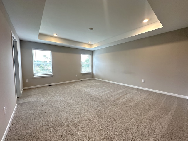 carpeted empty room featuring a raised ceiling