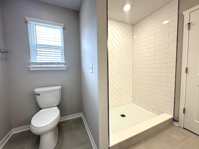 bathroom with toilet, tile patterned flooring, and tiled shower