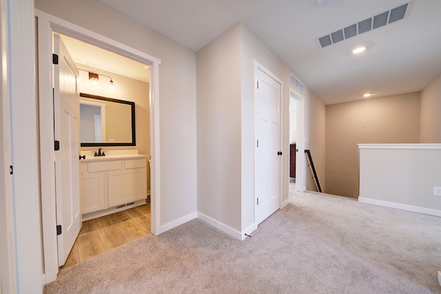 hallway with sink and light colored carpet