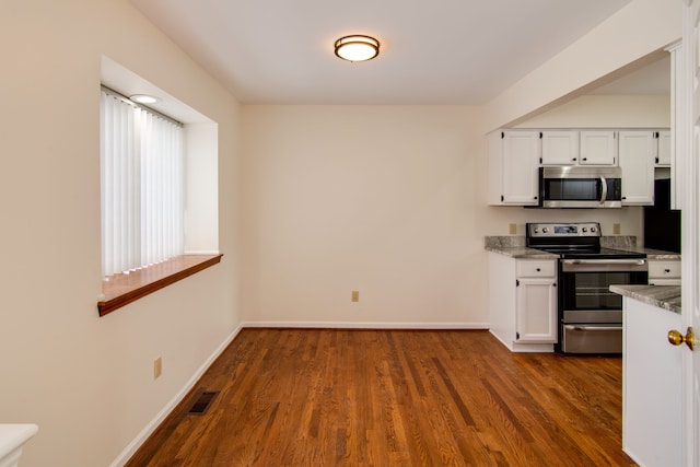 kitchen with light stone counters, dark hardwood / wood-style flooring, white cabinets, and appliances with stainless steel finishes