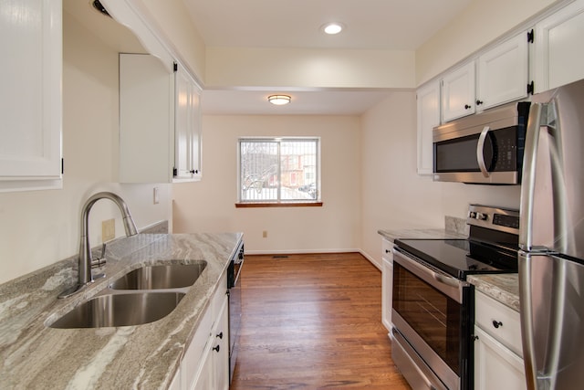 kitchen with white cabinets, light stone counters, sink, and appliances with stainless steel finishes