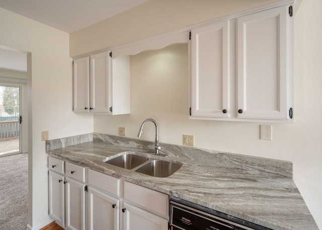 kitchen with white cabinetry, a sink, dishwasher, and light stone countertops