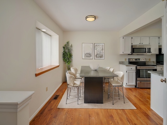 dining area featuring light wood-style floors, visible vents, and baseboards