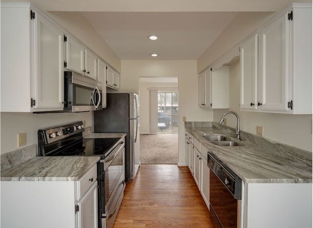 kitchen featuring recessed lighting, appliances with stainless steel finishes, light wood-style floors, white cabinetry, and a sink