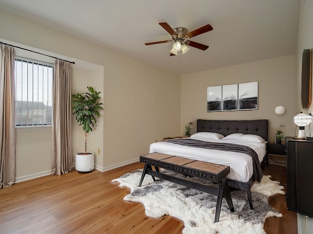 bedroom with light wood-style flooring, baseboards, and a ceiling fan