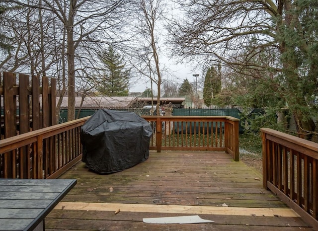 wooden terrace featuring a grill and fence