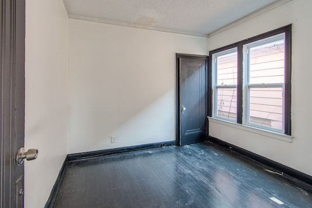 spare room featuring a textured ceiling, dark wood-type flooring, and ornamental molding