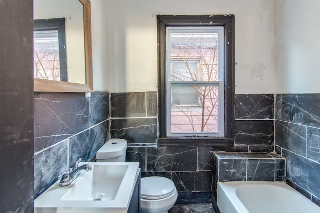 bathroom featuring sink, a bathtub, tile walls, and toilet