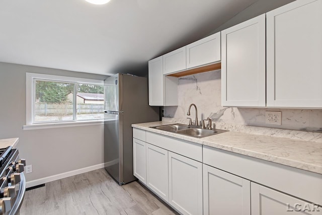 kitchen with white cabinets, light wood-type flooring, stainless steel appliances, and sink