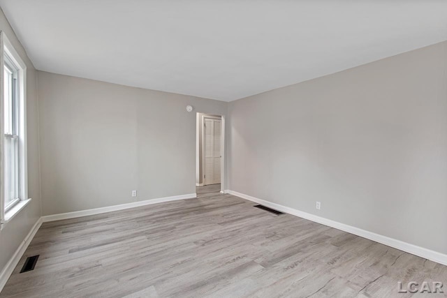 empty room featuring a healthy amount of sunlight and light hardwood / wood-style floors