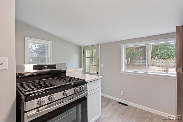 kitchen with gas range, light hardwood / wood-style flooring, white cabinets, and vaulted ceiling