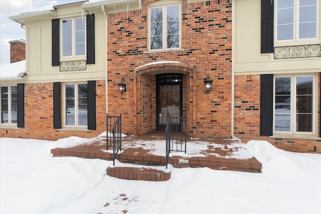 snow covered property entrance with brick siding