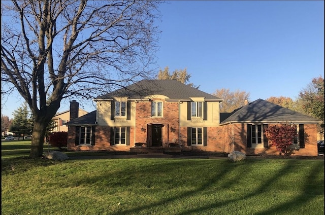 view of front of house featuring brick siding, a chimney, and a front lawn