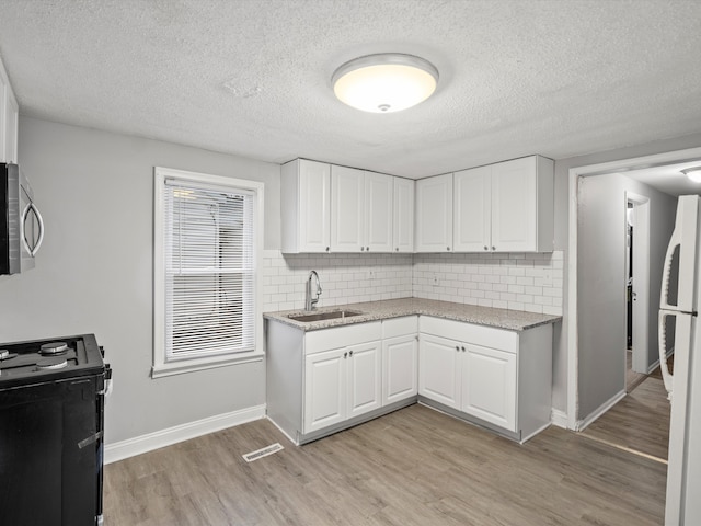 kitchen with sink, white cabinets, black electric range, and white refrigerator