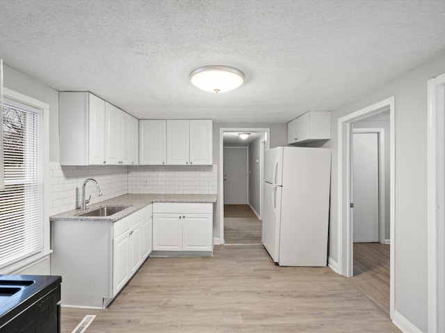 kitchen featuring backsplash, white cabinets, white refrigerator, sink, and light hardwood / wood-style flooring