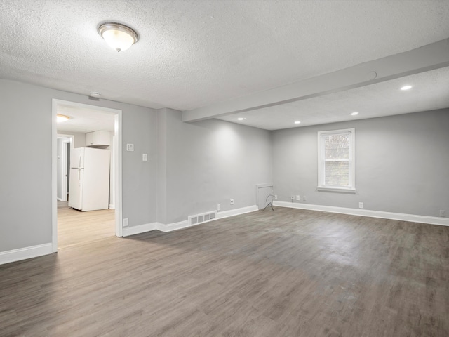 spare room featuring wood-type flooring and a textured ceiling