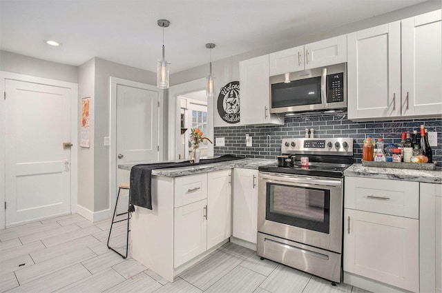 kitchen featuring stainless steel appliances, hanging light fixtures, white cabinets, and backsplash