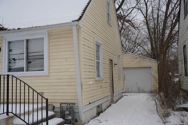 view of snow covered exterior featuring an outbuilding and a garage