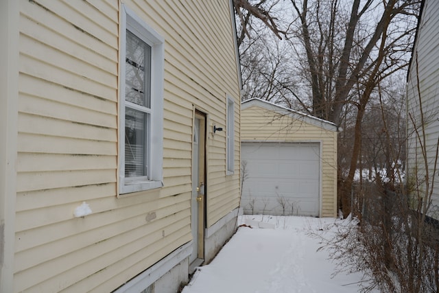 view of snowy exterior with a garage and an outbuilding