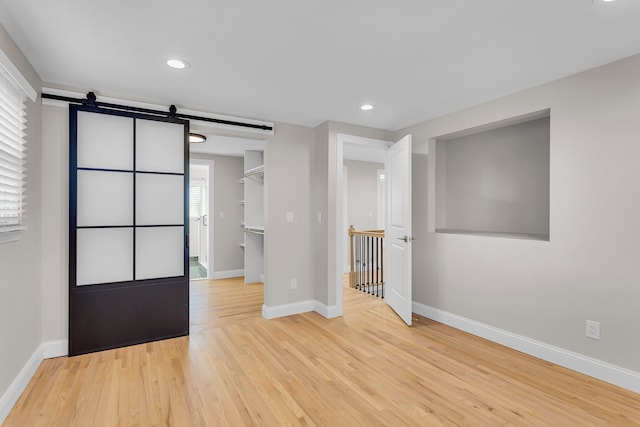 empty room featuring a barn door and light hardwood / wood-style floors