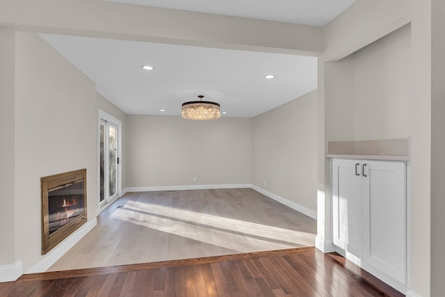 unfurnished living room with a chandelier and wood-type flooring