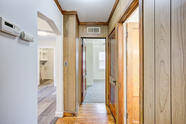 corridor featuring light wood-type flooring and ornamental molding