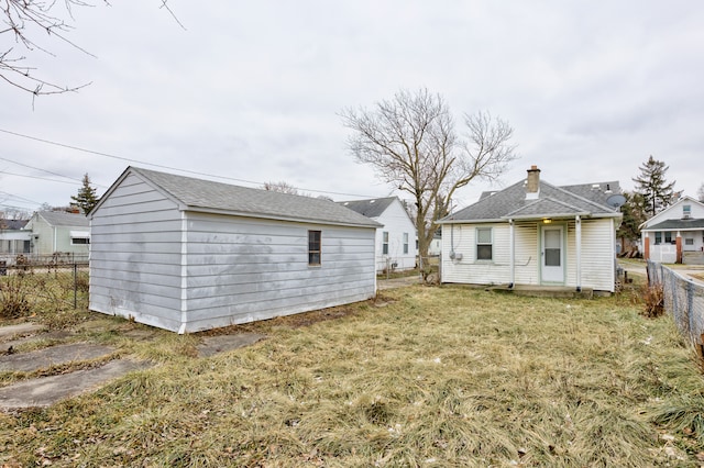 rear view of property with a lawn and an outbuilding