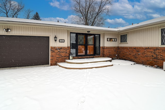 snow covered property entrance featuring a garage