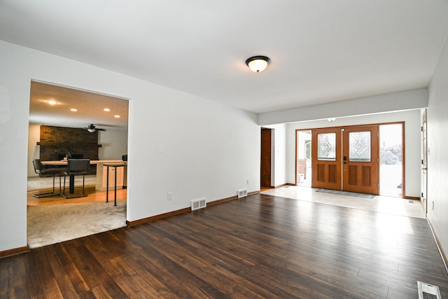 foyer featuring wood-type flooring, french doors, and a large fireplace