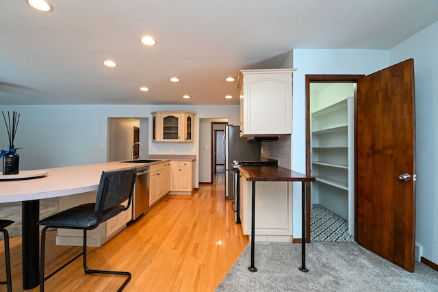 kitchen with light hardwood / wood-style floors, dishwasher, kitchen peninsula, and sink