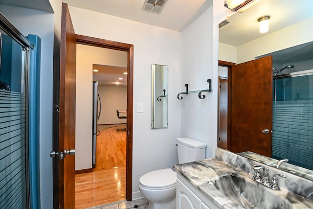 bathroom featuring a shower with shower door, toilet, vanity, and tile patterned flooring