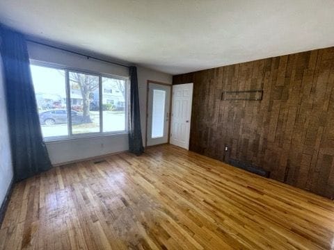 spare room featuring wood walls and light hardwood / wood-style flooring