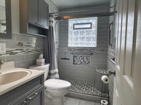 bathroom featuring tile patterned flooring, vanity, toilet, and curtained shower