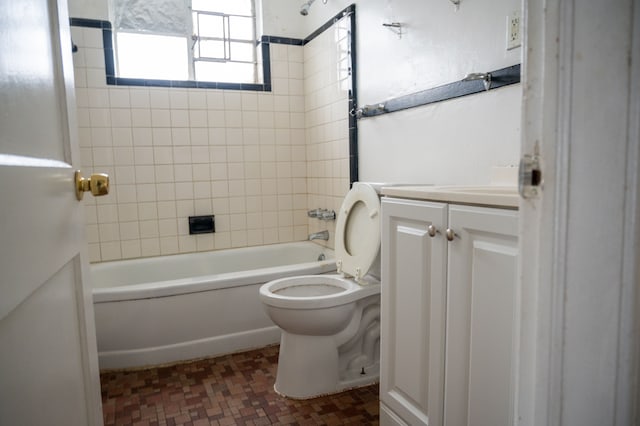 full bathroom with tiled shower / bath, vanity, and toilet