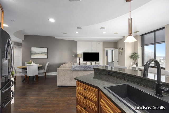 kitchen featuring dark wood-type flooring, black fridge, sink, and pendant lighting