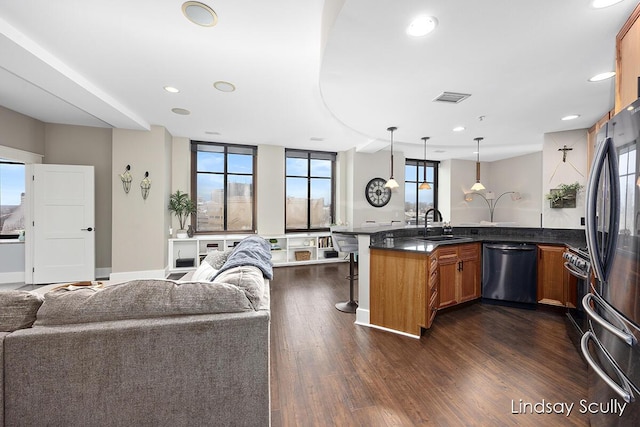 kitchen with a kitchen bar, appliances with stainless steel finishes, dark hardwood / wood-style flooring, sink, and pendant lighting