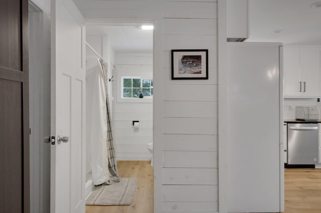 bathroom featuring wood walls, toilet, and wood-type flooring