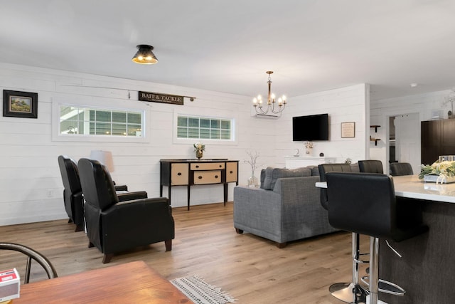 living room featuring light wood-type flooring, a notable chandelier, and wood walls