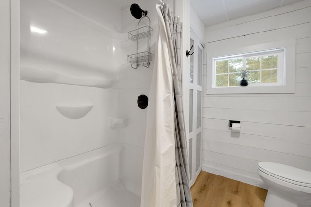 bathroom featuring wooden walls, toilet, a shower with shower curtain, and hardwood / wood-style flooring