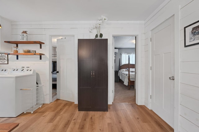 laundry room with wood walls, light hardwood / wood-style flooring, and washer and dryer