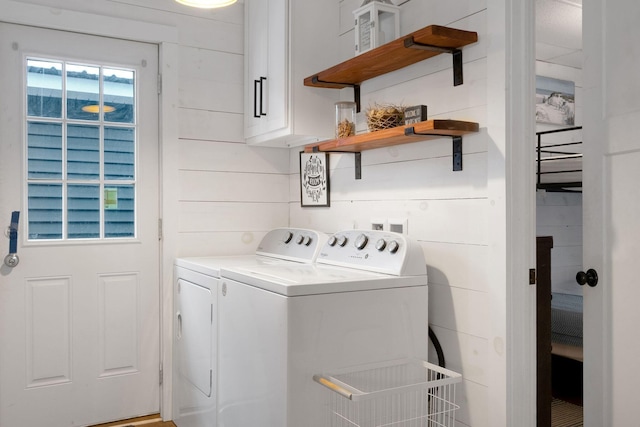 washroom featuring cabinets, independent washer and dryer, and wooden walls