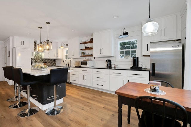 kitchen featuring a kitchen island, backsplash, decorative light fixtures, white appliances, and white cabinets