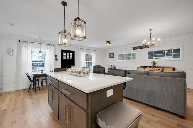 kitchen with pendant lighting, a kitchen island, light hardwood / wood-style flooring, and a healthy amount of sunlight