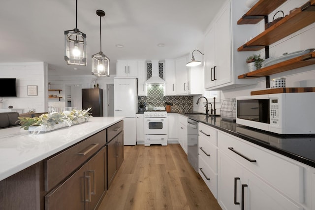 kitchen with white cabinets, decorative light fixtures, white appliances, and custom range hood